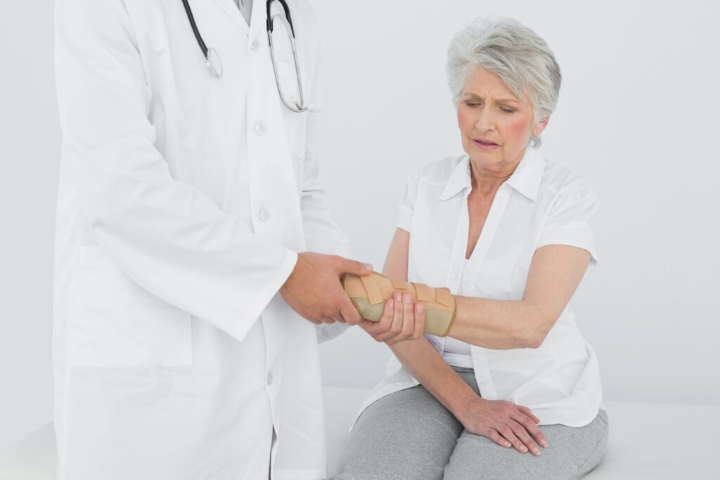 Male physiotherapist examining senior womans wrist 13339 13779 Male physiotherapist examining senior womans wrist 13339 13779